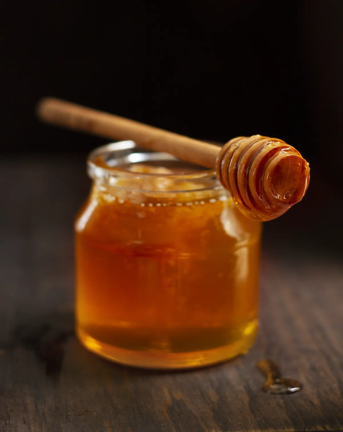 Bote de cristal con miel y cuchara de madera